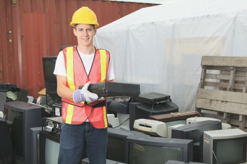 Team loading rubbish into a skip with protective gear