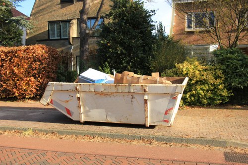 Safety cones and signage around a skip on the roadside