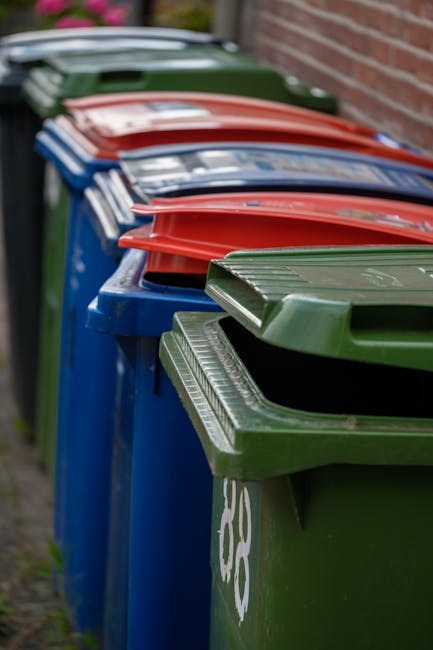 A large pile of various waste materials and rubbish bags situated on a paved urban footpath in front of a commercial building with a blue scaffolding framework. The waste includes black and colored tr